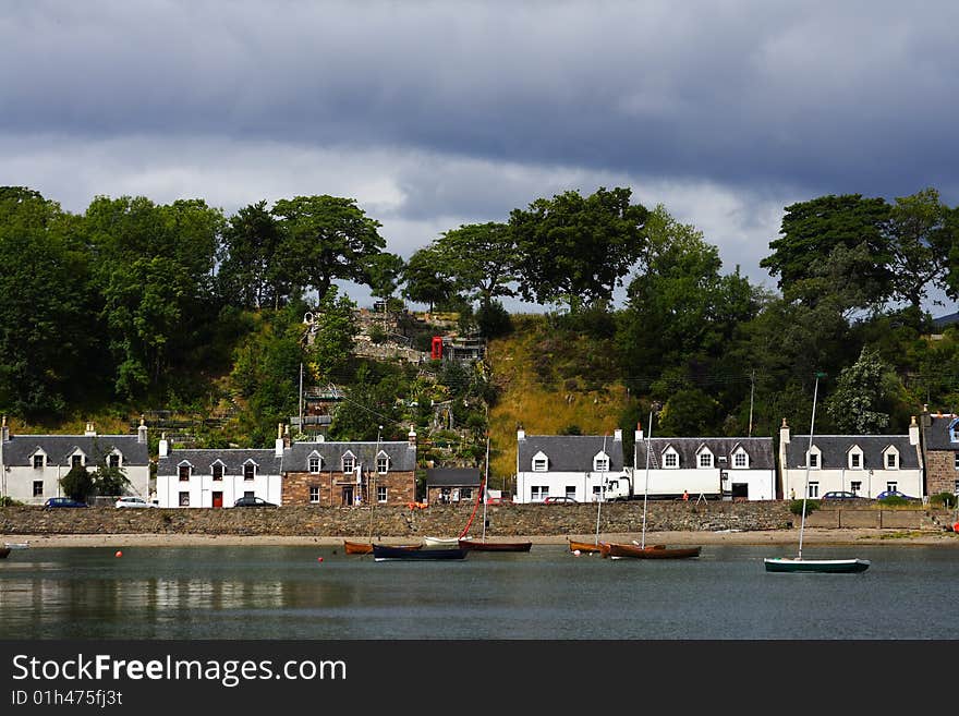 Plockton village and loch carron in scotland during summer with sailing boats at first plan. Plockton village and loch carron in scotland during summer with sailing boats at first plan