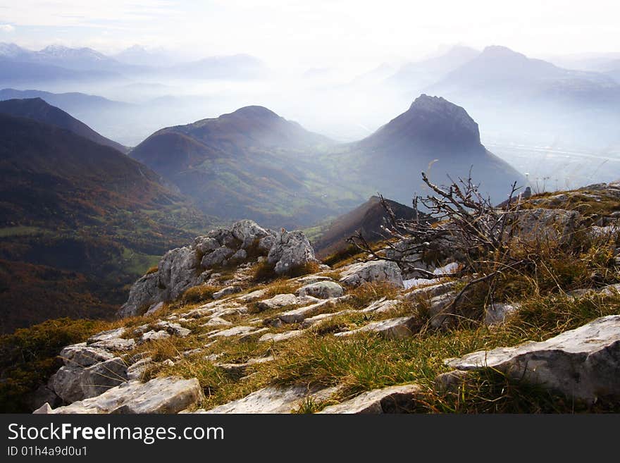 View from the top in chartreuse (french alps). View surrounding grenoble town and peaks. Summit with limestone rocks.