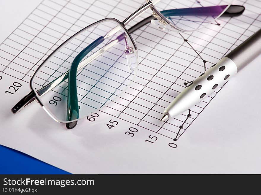 A pen and glasses composed over a business chart of earnings growth.