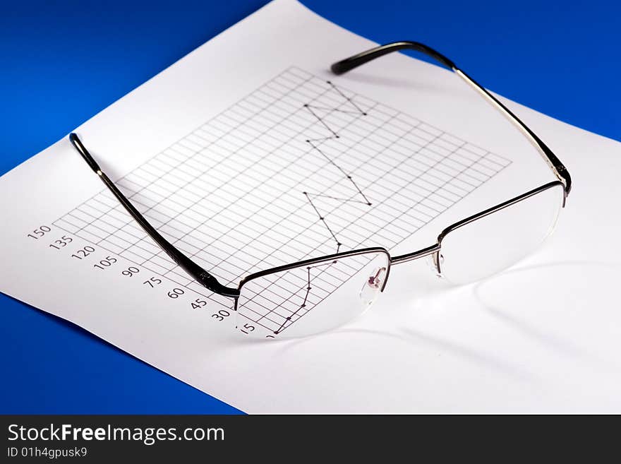 Glasses composed over a business chart of earnings growth.