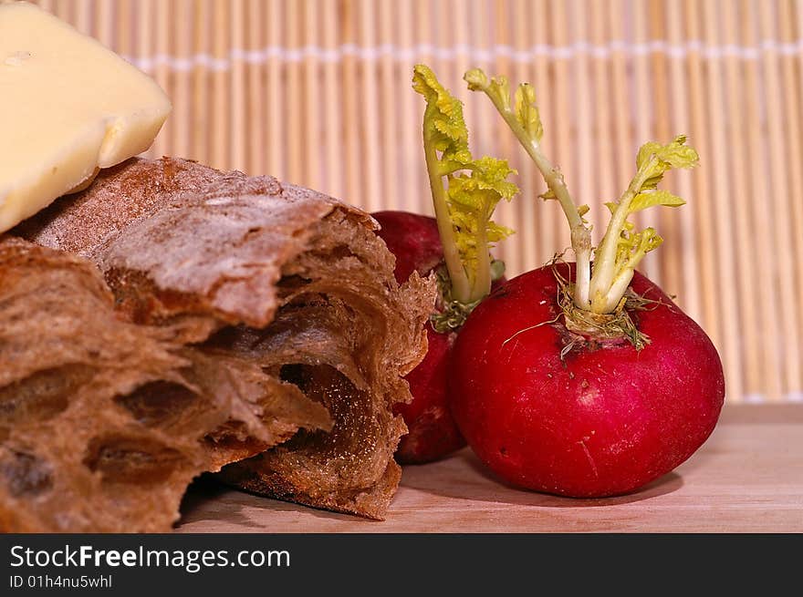 Still-life with ciabatta, redish and cheese on wooden plate. Still-life with ciabatta, redish and cheese on wooden plate