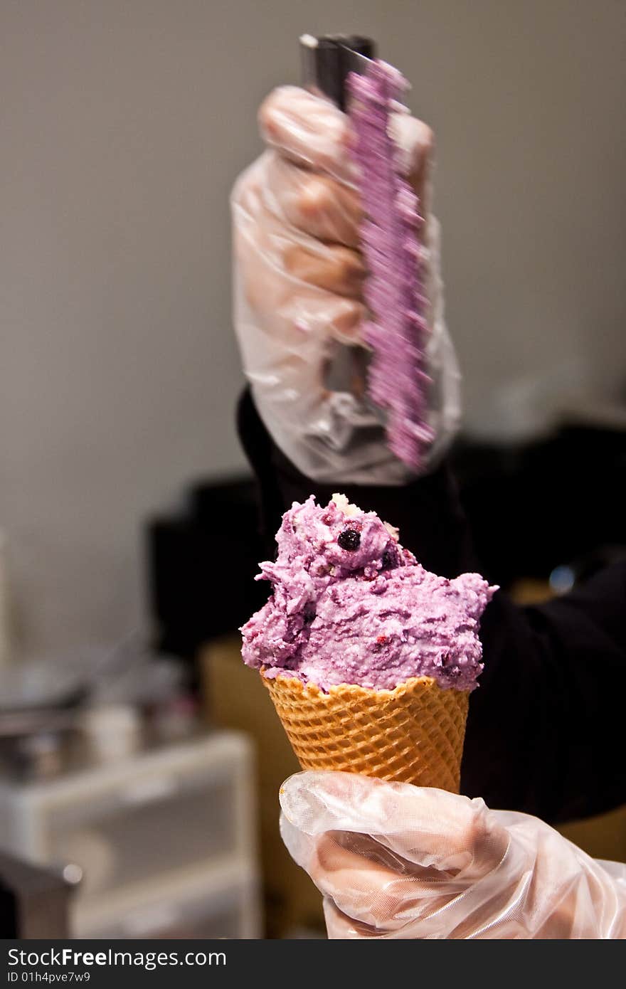 Person wearing latex gloves preparing ice cream on a cone