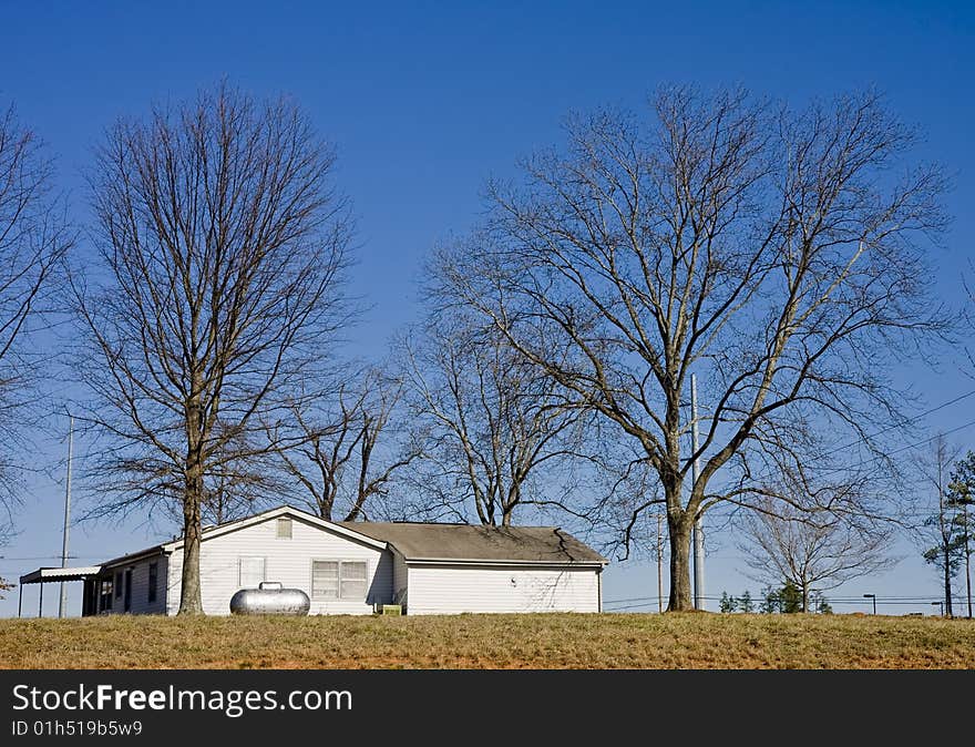 An old white farmhouse on a hill between oak trees. An old white farmhouse on a hill between oak trees