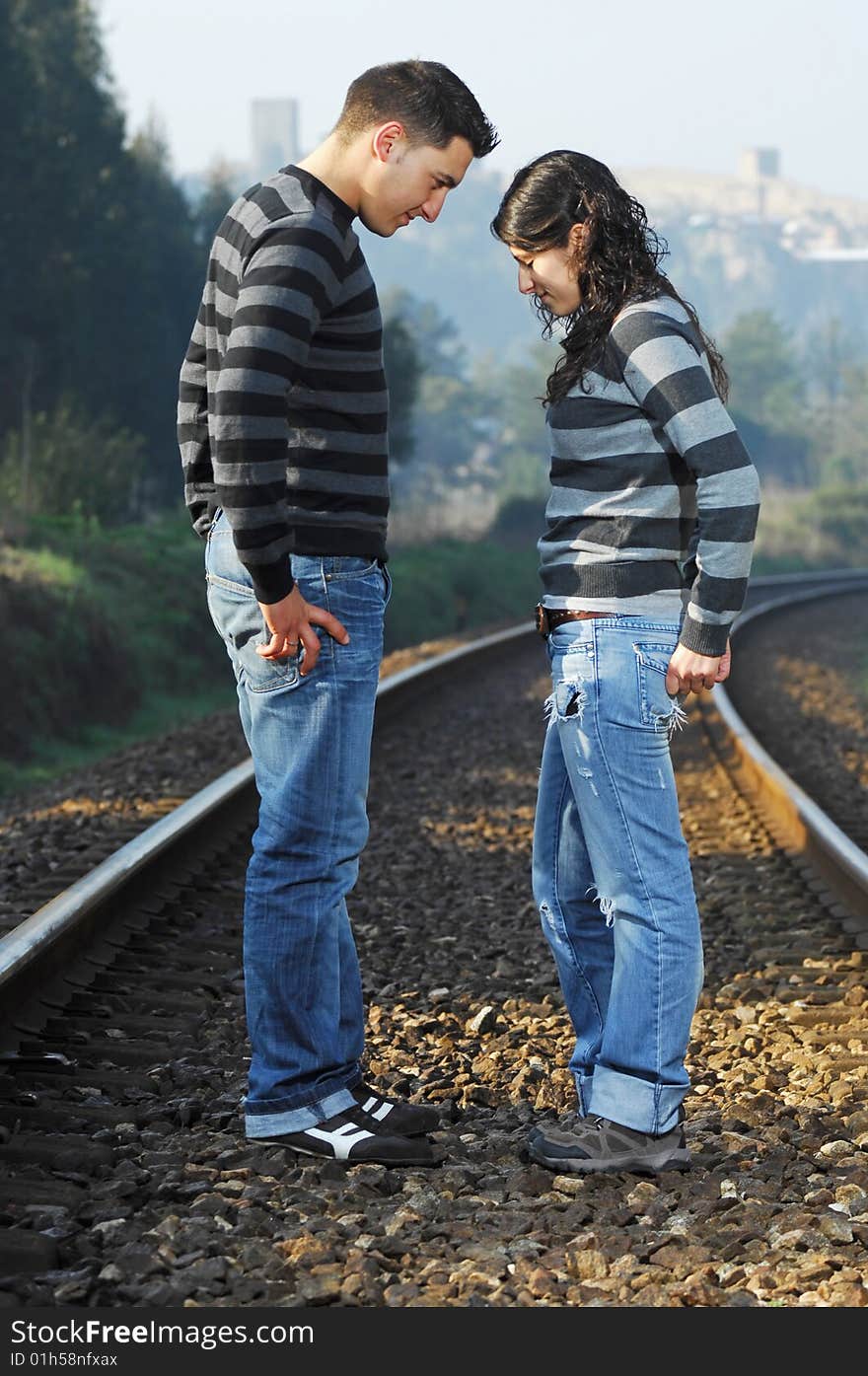 Young couple looking each other on railway tracks. Young couple looking each other on railway tracks