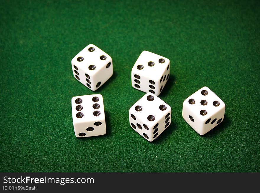 5 white dice sitting on green felt. 5 white dice sitting on green felt.