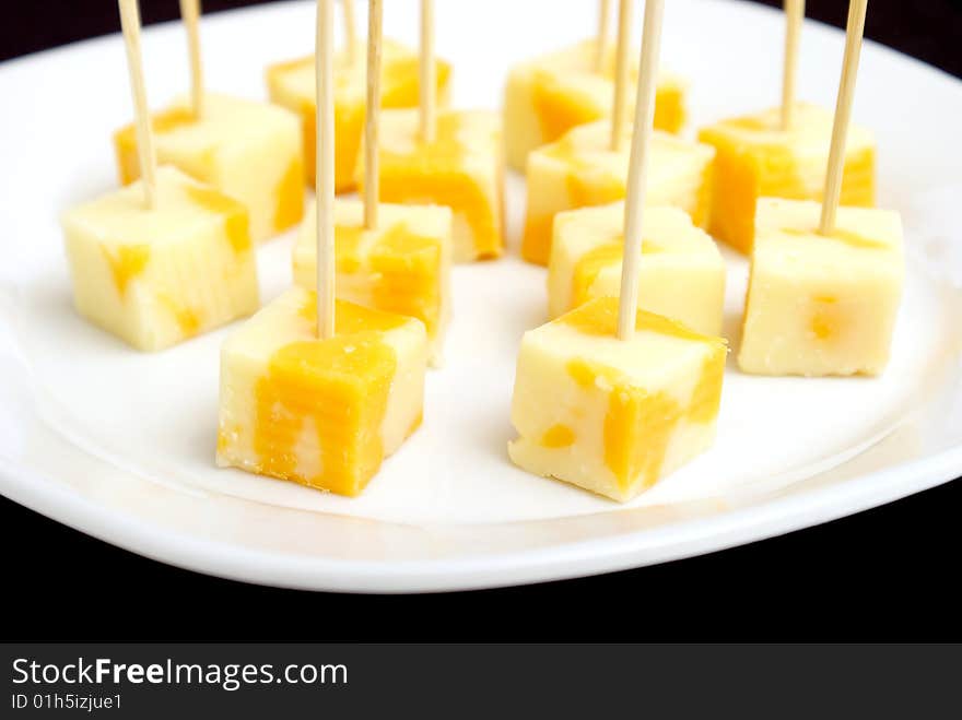 A plate of cheese cubes with toothpicks.