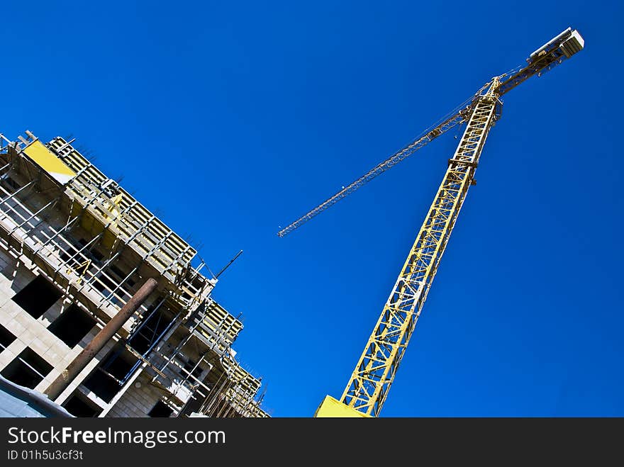 A multistory dwelling house under construction with a jib crane.