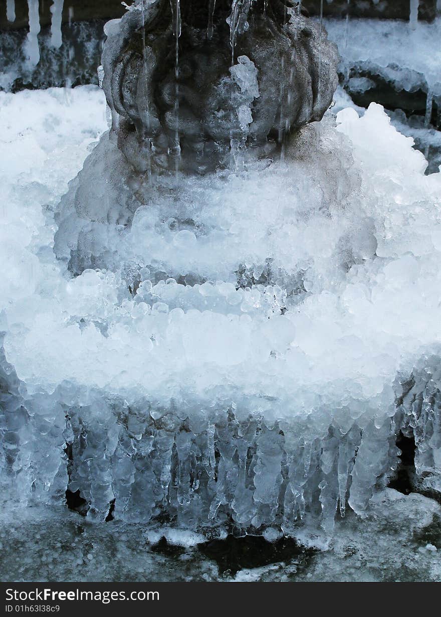 A close-up of a frozen fountain with multiple icicles.