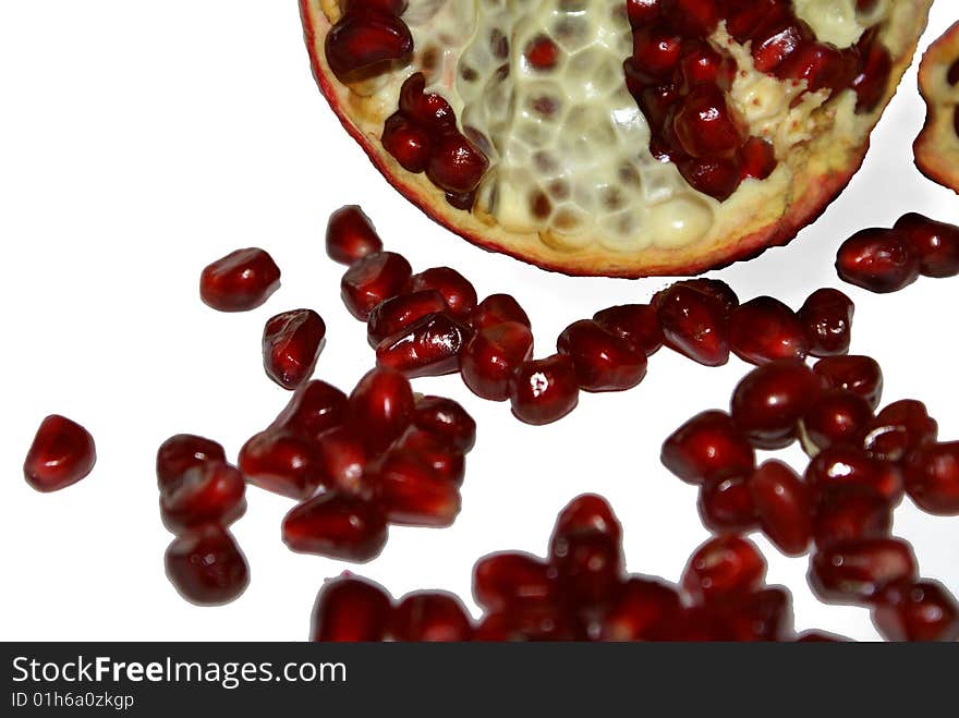 Grains of pomegranate, lie near the bisected fruit. Grains of pomegranate, lie near the bisected fruit