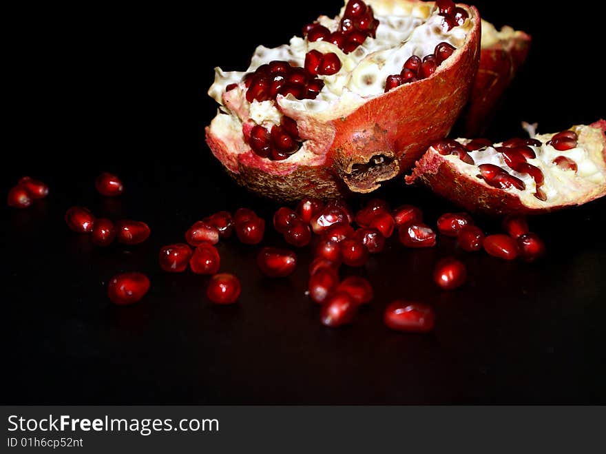 Grains of pomegranate, lie near the bisected fruit. Grains of pomegranate, lie near the bisected fruit