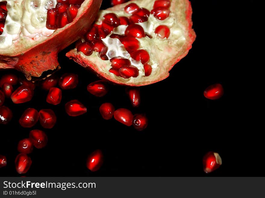 Grains of pomegranate, lie near the bisected fruit. Grains of pomegranate, lie near the bisected fruit