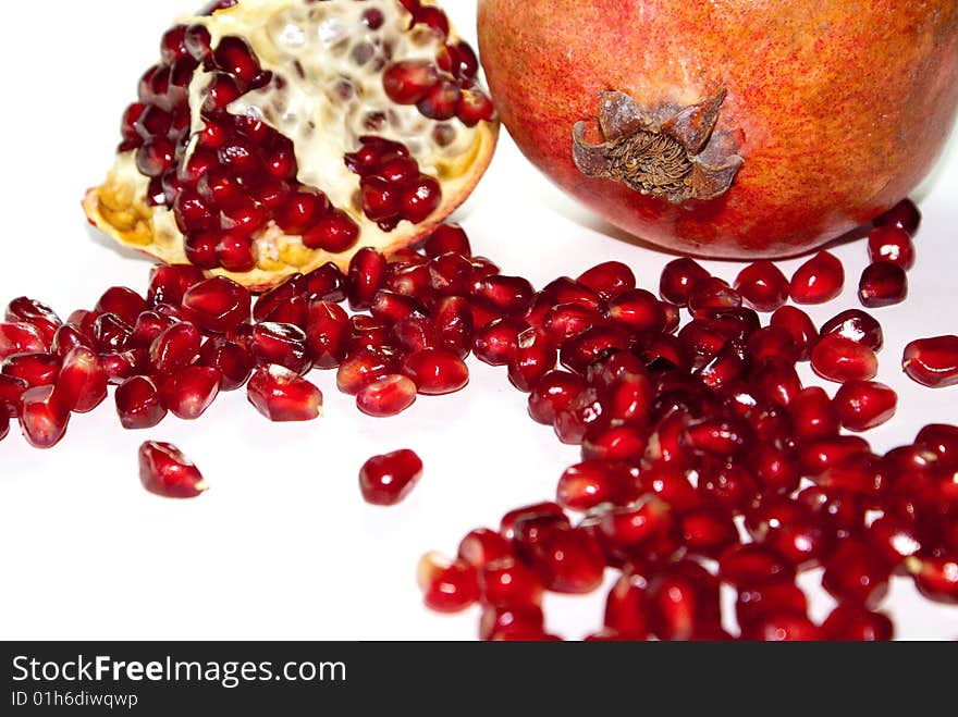 Grains of pomegranate, lie near the bisected fruit. Grains of pomegranate, lie near the bisected fruit