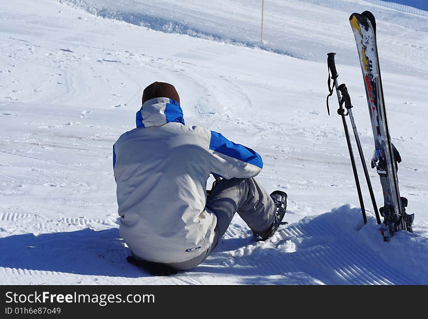 Tired ski rider sitting on snow