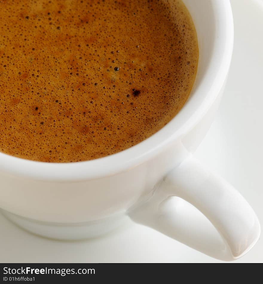 Fresh coffee in a white cup on a plate, high angle view.