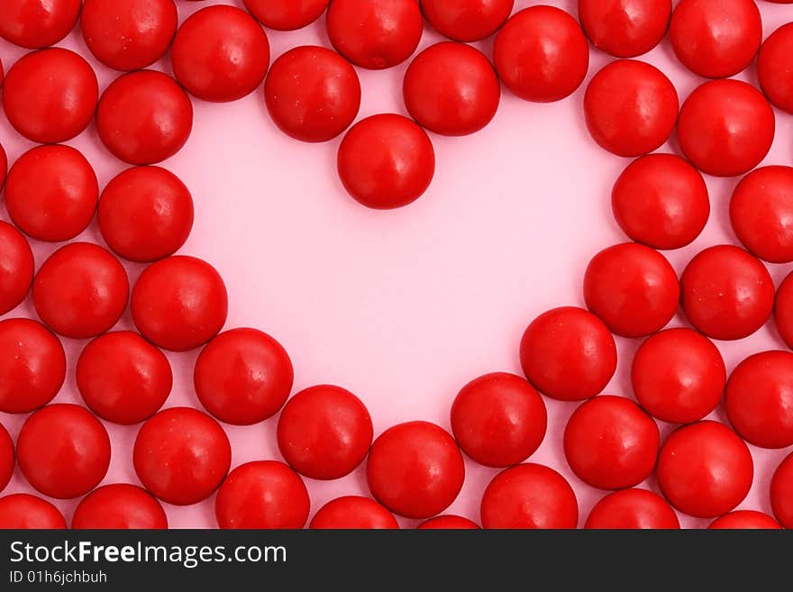 Heart made out of red smarties on pink background, coopy space. Heart made out of red smarties on pink background, coopy space.