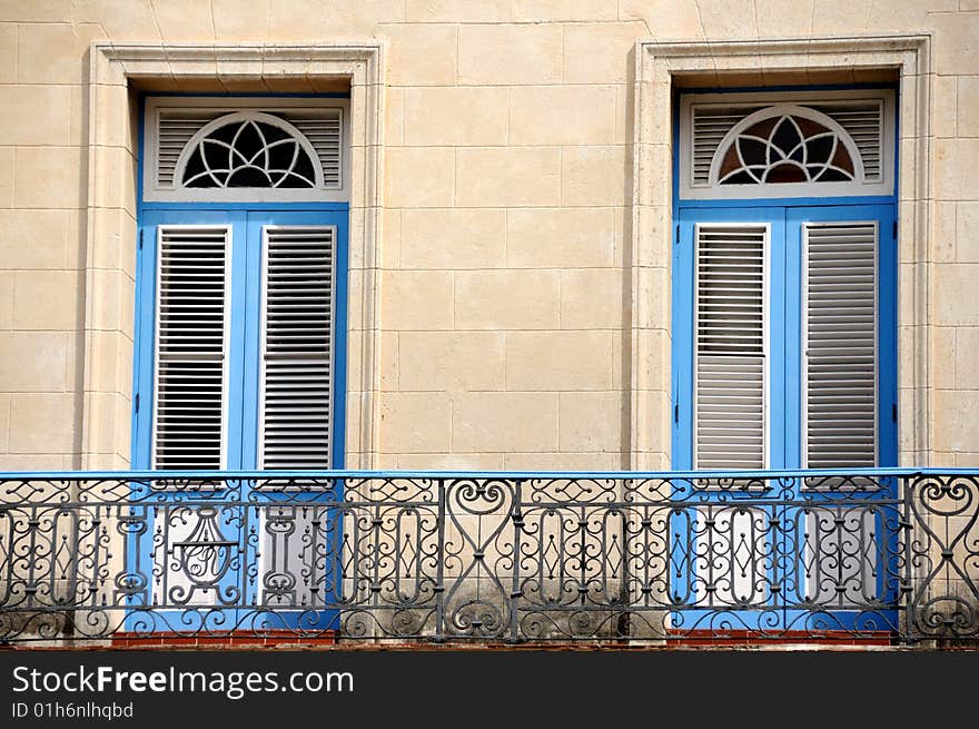 A classic balcony with shuttered twin blue framed doors