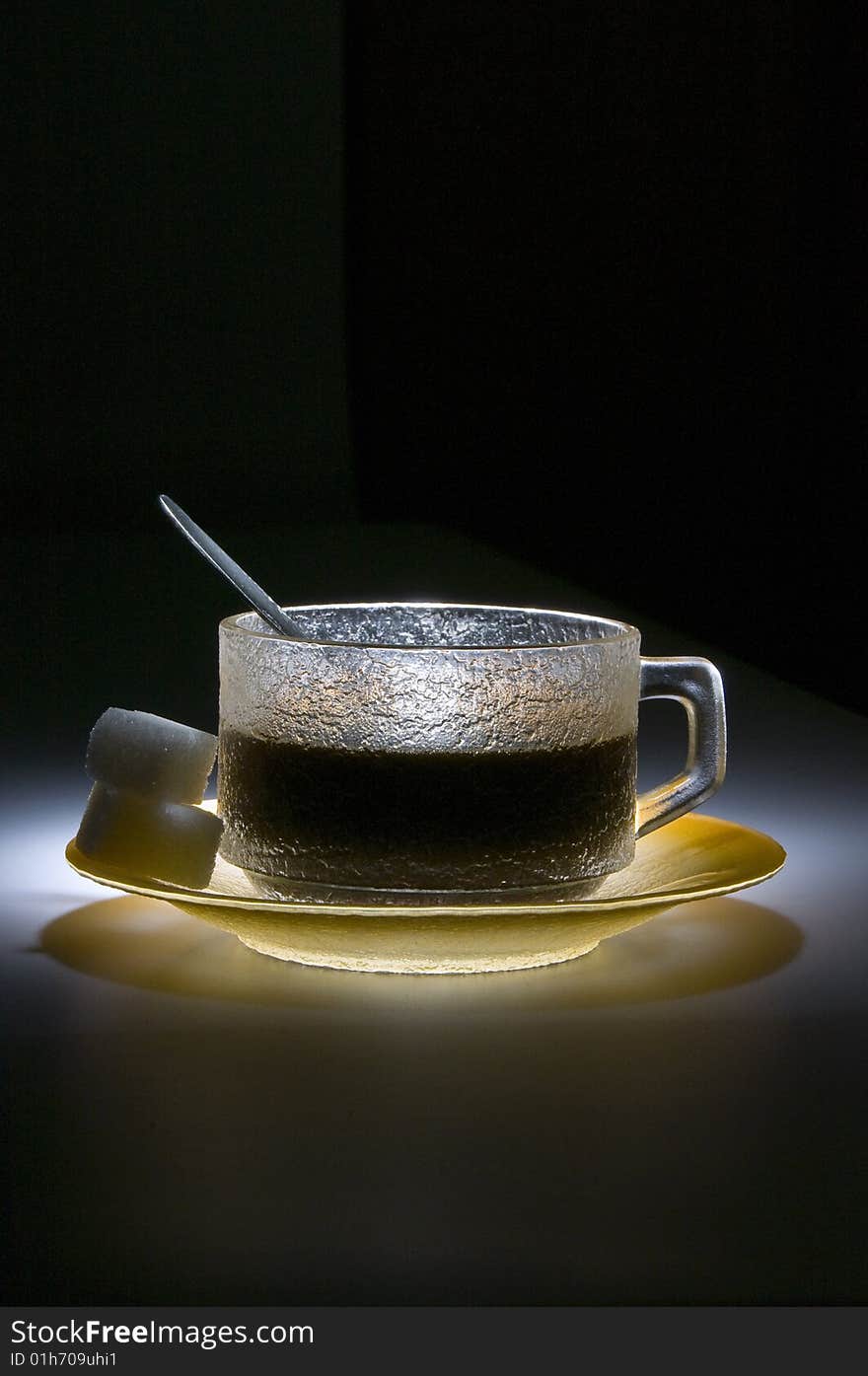 Cup of coffee in the dark, lighted by the spotligth