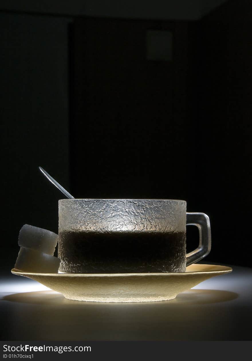 Cup of coffee in the dark, lighted by the spotligth