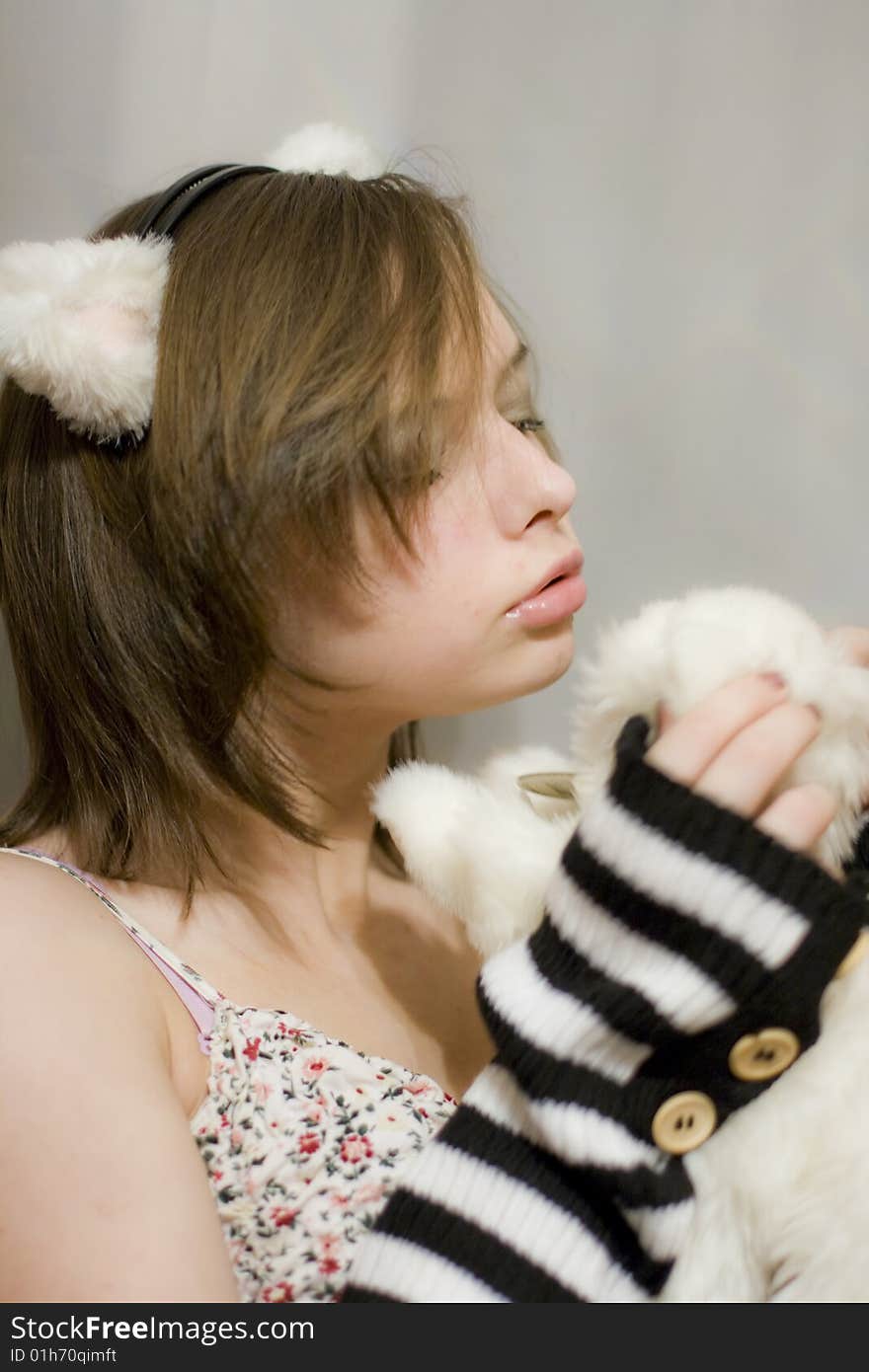 Sweet girl with the ears on your head. Beautiful girl holds a toy - white kitten. Sweet girl with the ears on your head. Beautiful girl holds a toy - white kitten