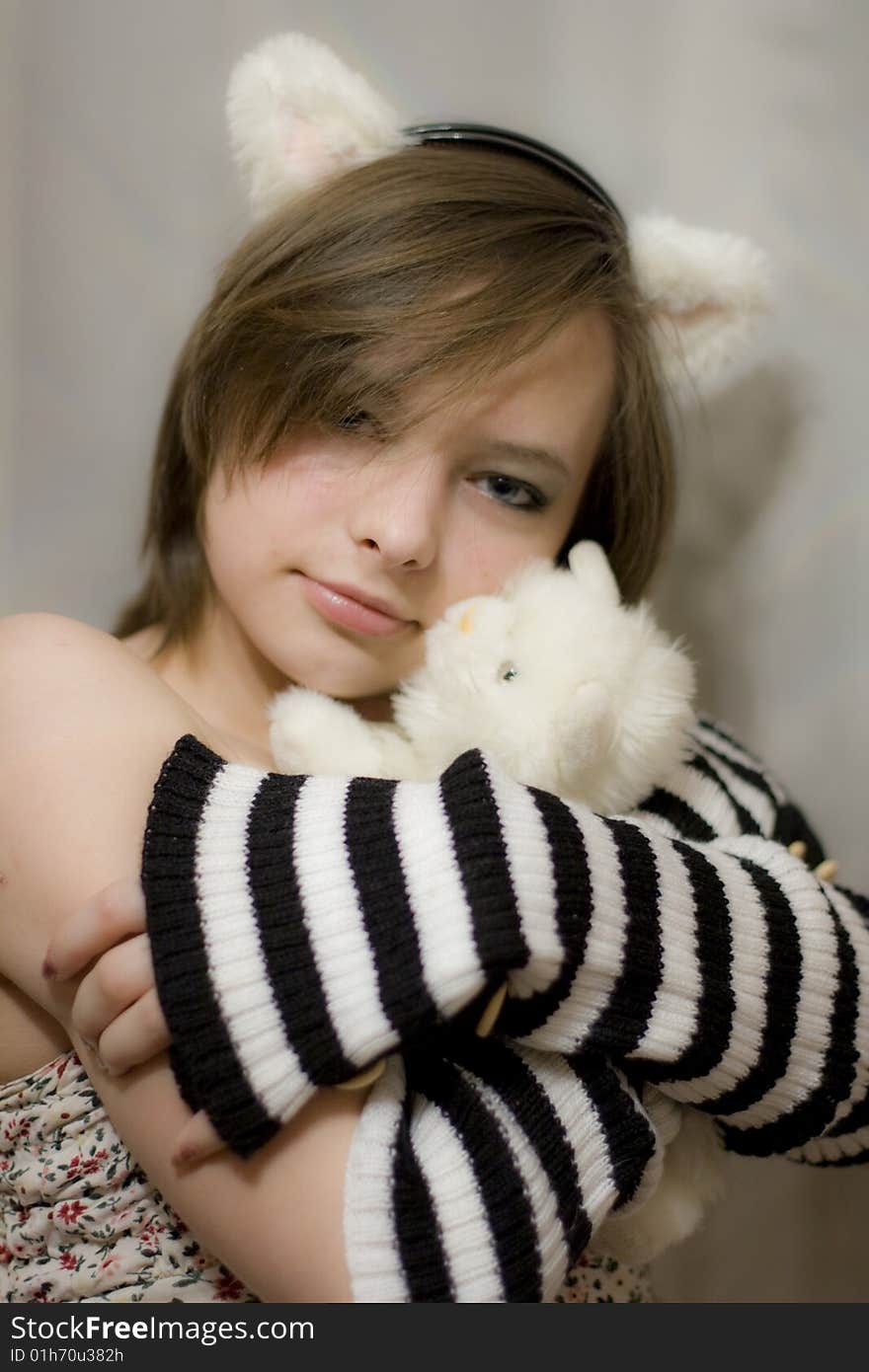 Sweet girl with the ears on your head. Beautiful girl holds a toy - white kitten. Sweet girl with the ears on your head. Beautiful girl holds a toy - white kitten