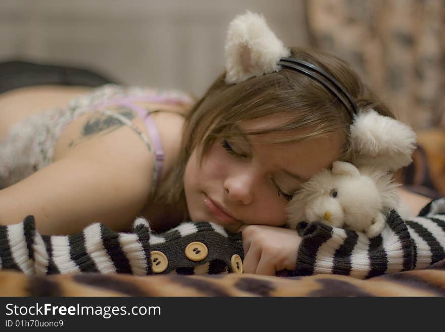 Sweet girl with the ears on your head. Beautiful girl holds a toy - white kitten. Sweet girl with the ears on your head. Beautiful girl holds a toy - white kitten