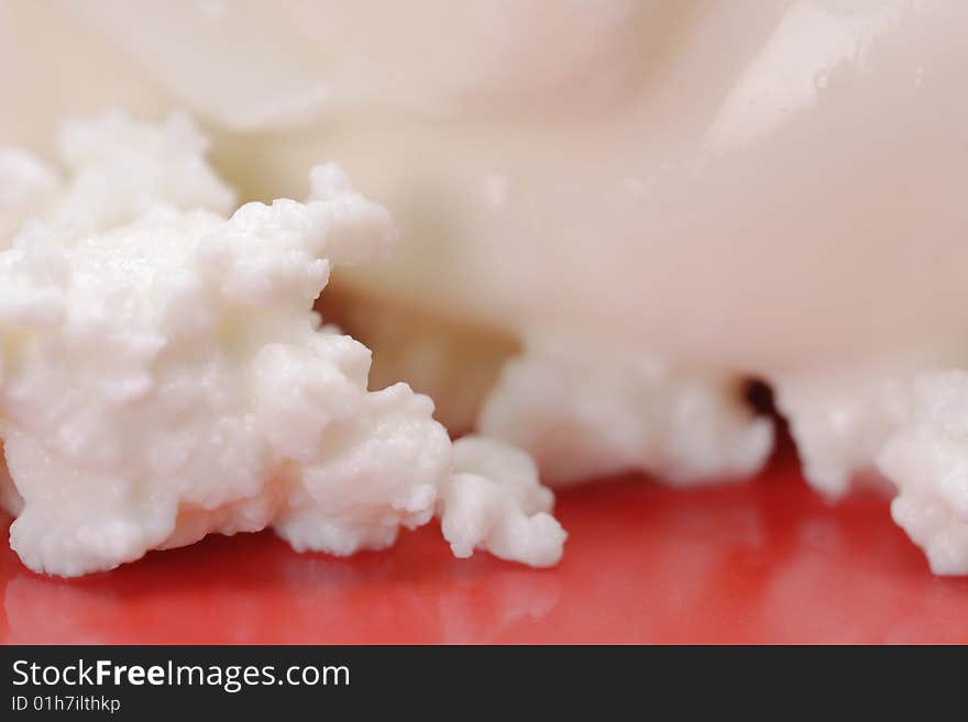 Cottage cheese with soured cream on the red plate. Close-up. Narrow depth of field. Cottage cheese with soured cream on the red plate. Close-up. Narrow depth of field.