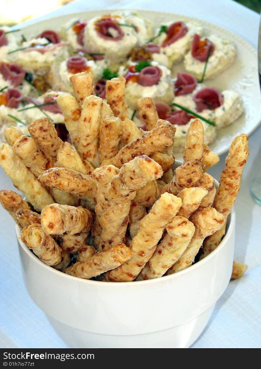 Bowl of bread sticks with a plate of sandwiches. Bowl of bread sticks with a plate of sandwiches