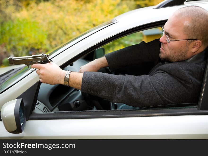 Angry man with gun driving car. Angry man with gun driving car