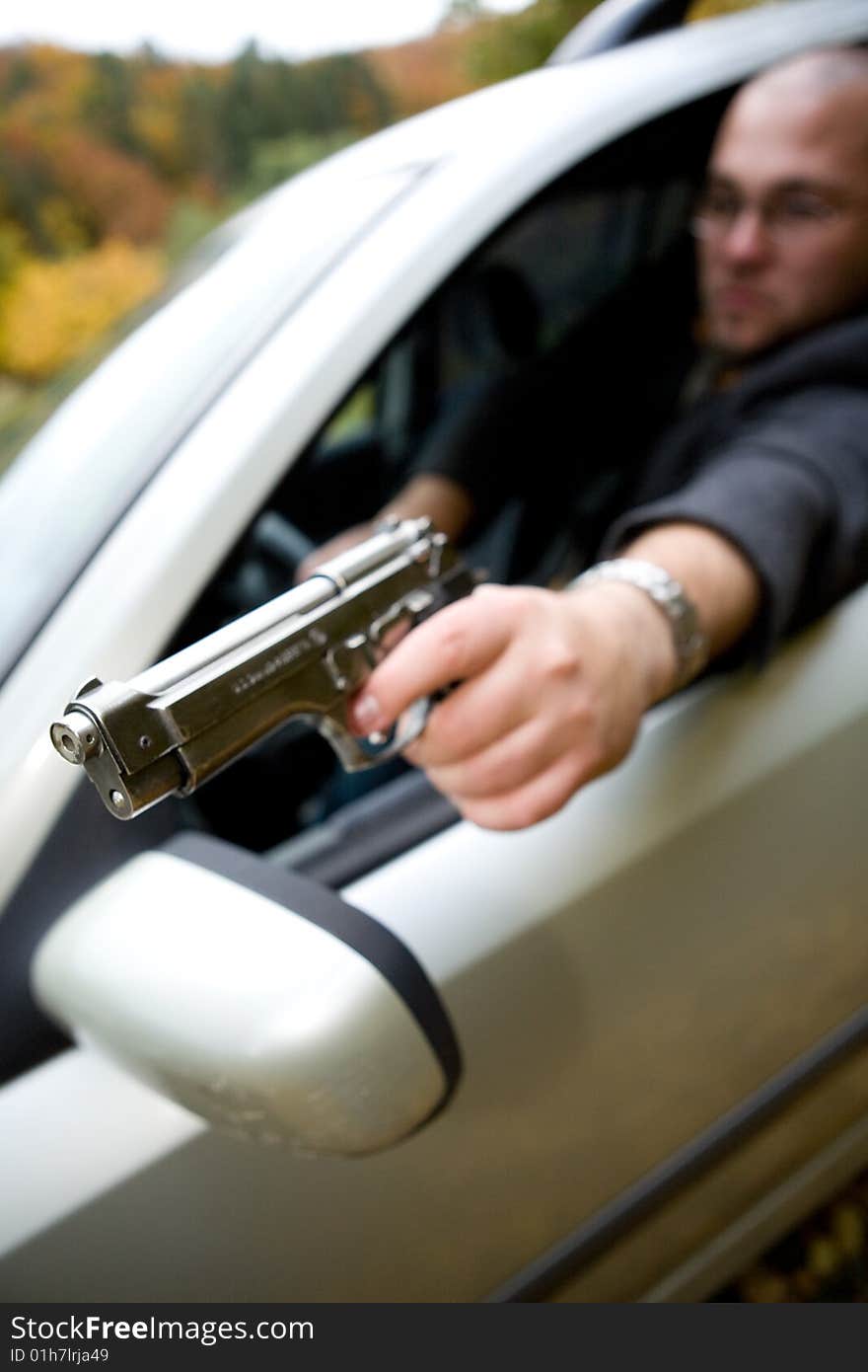 Angry man with gun driving car. Angry man with gun driving car