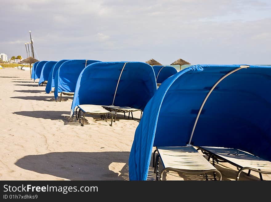 Blue Beach Shelters and Umbrellas on a beach on a cloudy day