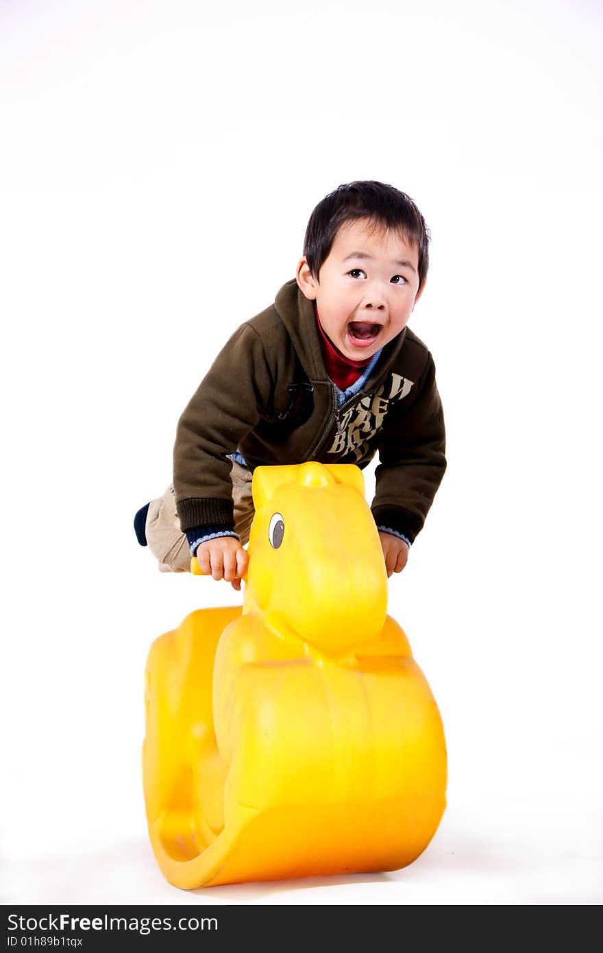 A picture of a little chinese boy riding a yellow plastic toy horse and having great fun. A picture of a little chinese boy riding a yellow plastic toy horse and having great fun