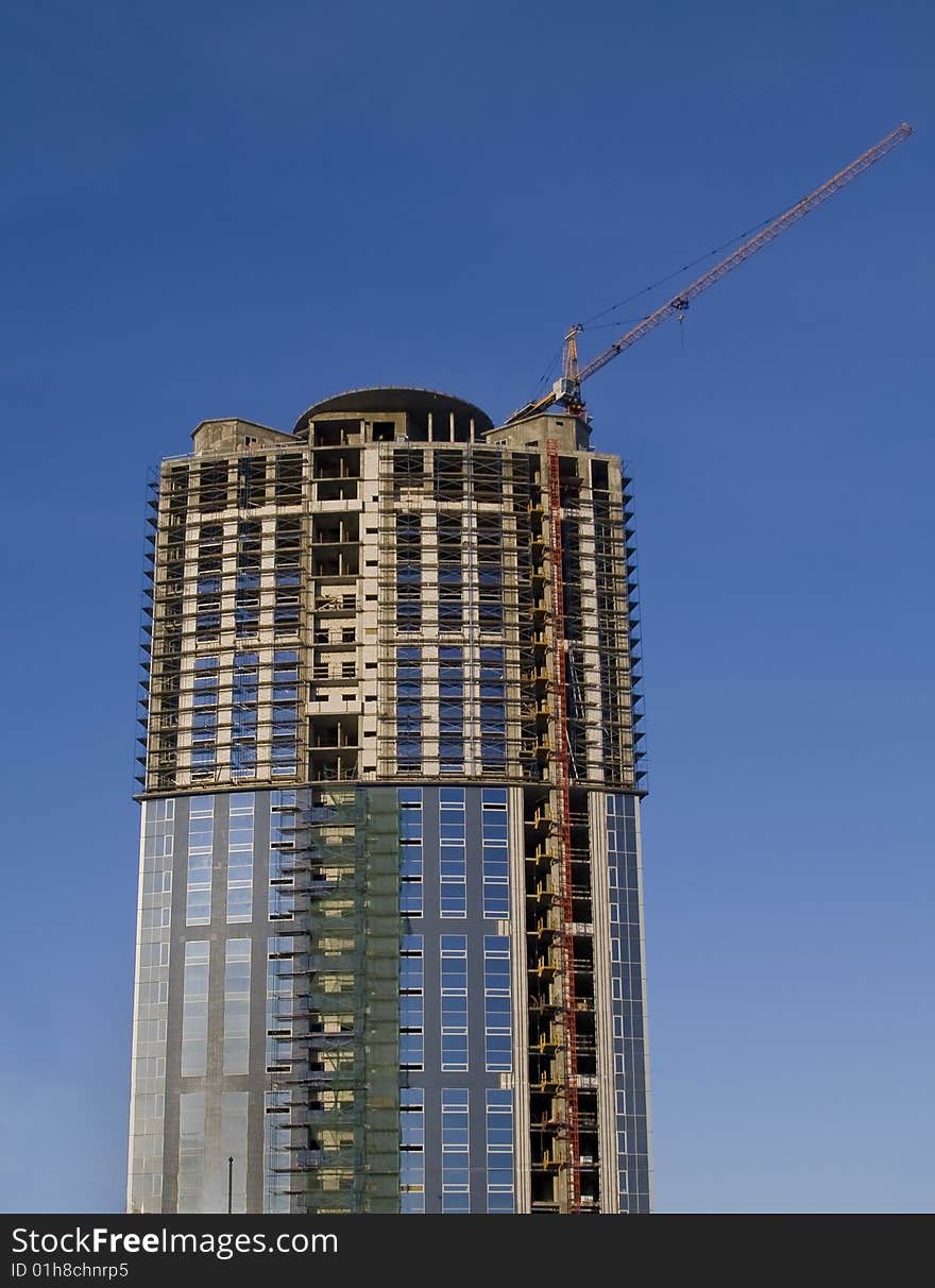 Cranes and building construction of a skyscraper early morning against the dark blue sky