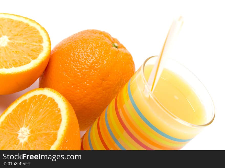 Glass of juice and oranges closeup on white