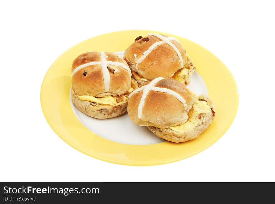 Three toasted and buttered hot cross buns on a plate