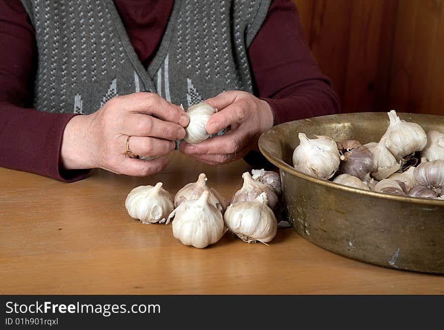 The old woman touches garlic sitting for a table