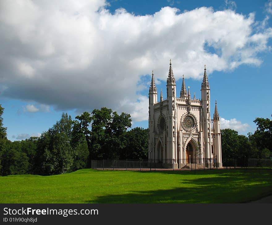 Gothic chapel on green glade whith blue sky