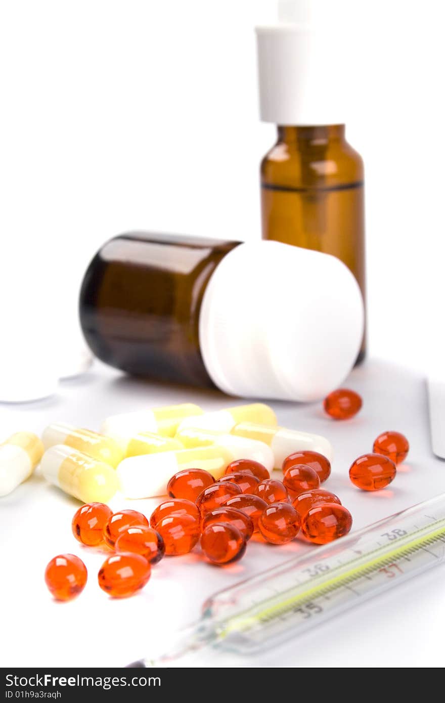 Thermometer and different pills closeup on white background