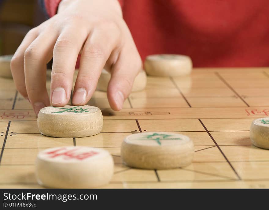 A boy is moving a piece of Chinese chess. A boy is moving a piece of Chinese chess.