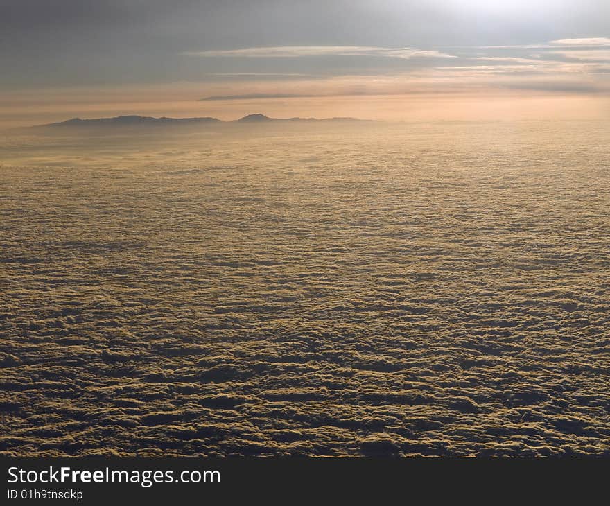 The sun declines above the clouds. A mountain is looming on the background. The sun declines above the clouds. A mountain is looming on the background.