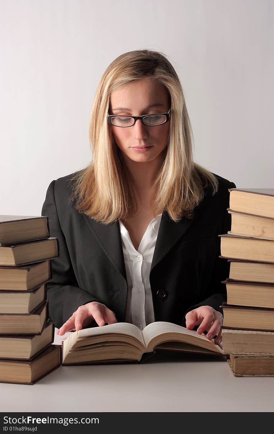 A young pretty woman reading a book and sitting on a table above a white background. A young pretty woman reading a book and sitting on a table above a white background