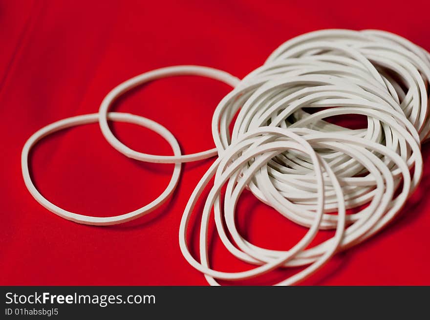 Some white elastic bands which used for magic show with a red background. Some white elastic bands which used for magic show with a red background.