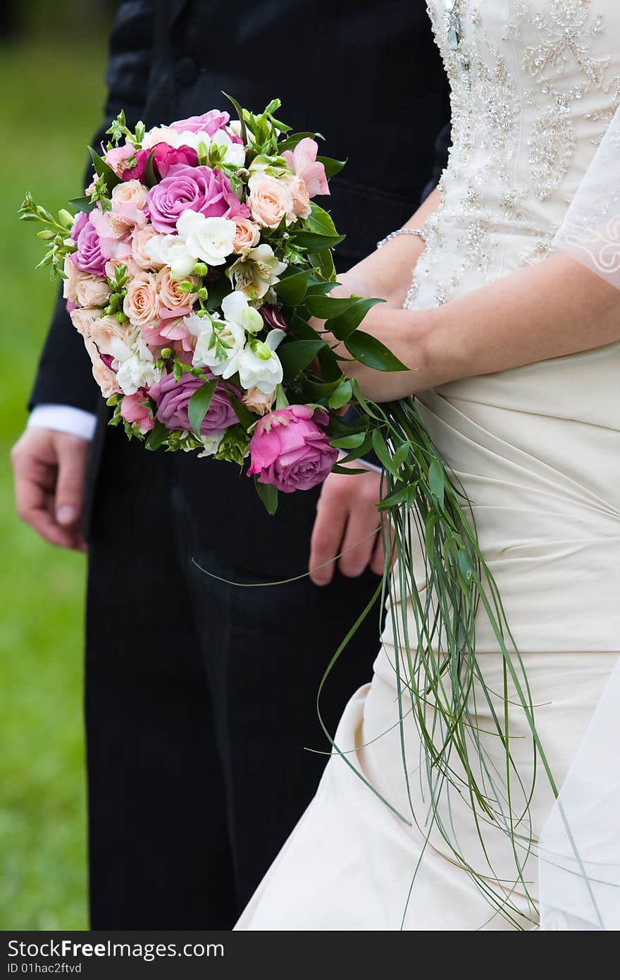 Bride and groom stand near each other with bouquet of roses. Bride and groom stand near each other with bouquet of roses