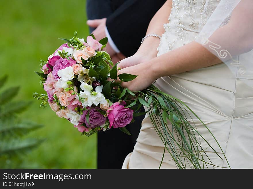 Bride and groom stand near each other with bouquet of roses. Bride and groom stand near each other with bouquet of roses