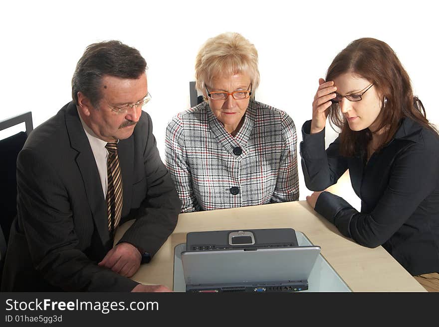 A business team of three sitting in front of a laptop. Isolated over white. A business team of three sitting in front of a laptop. Isolated over white.