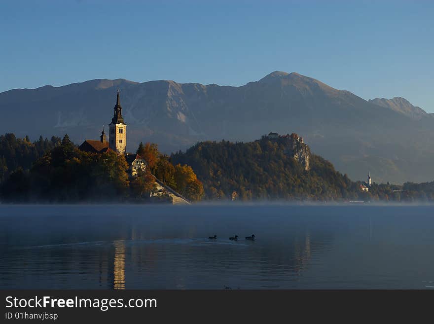 Lake Bled with church on island and castle on a rock in autumn morning