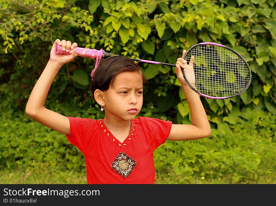 A girl with her badminton bat thinking seriously about something.