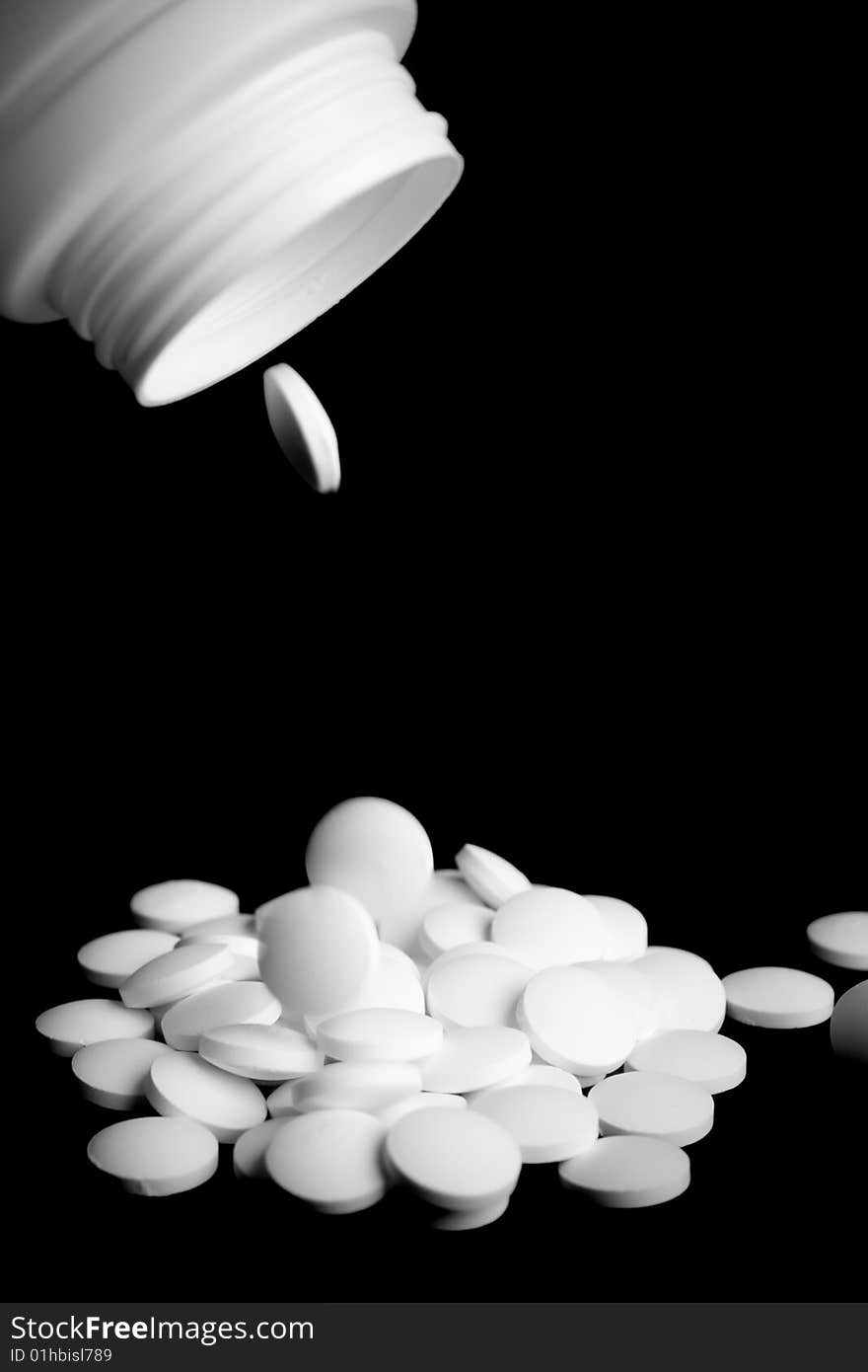 Bottle with white pills on black background