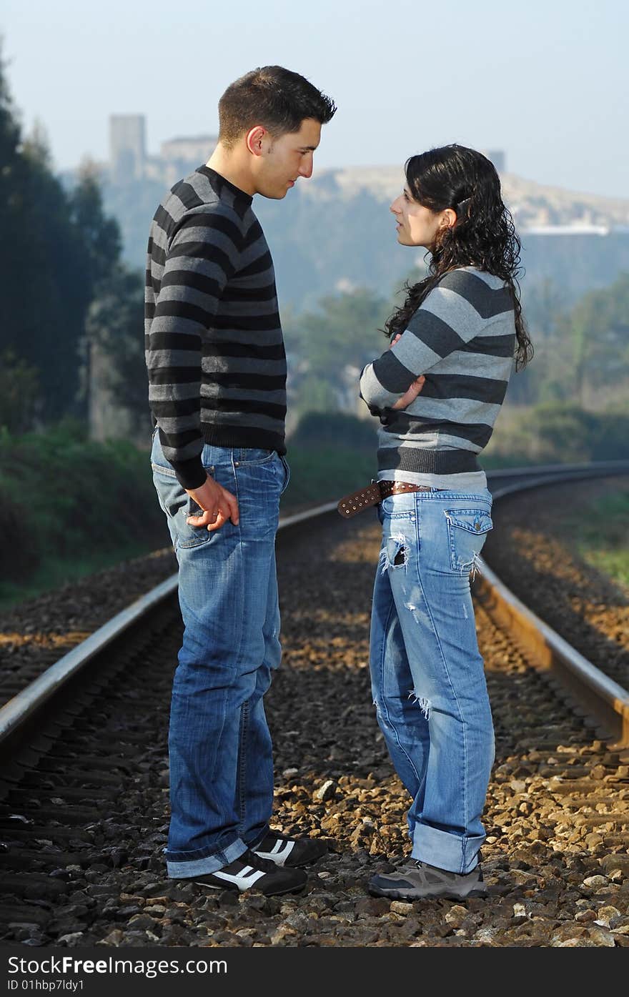 Young couple looking each other on railway tracks. Young couple looking each other on railway tracks