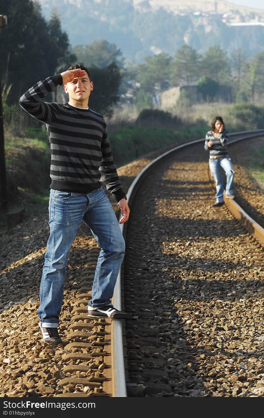 Young couple walking and looking for the train on the railway tracks. Young couple walking and looking for the train on the railway tracks