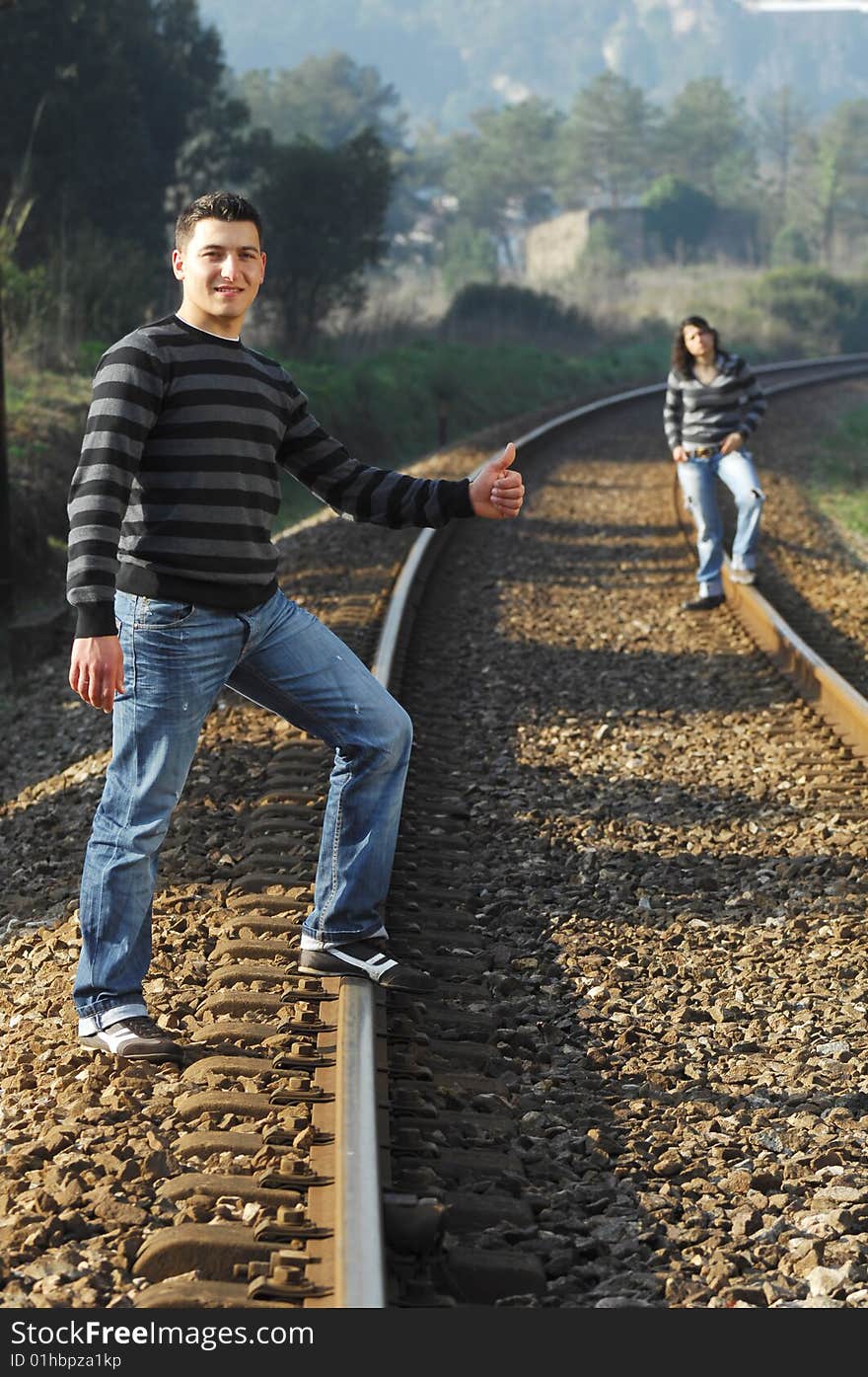 Young couple walking and looking for the train on the railway tracks. Young couple walking and looking for the train on the railway tracks